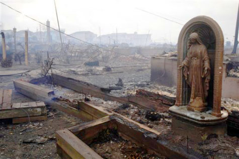 A statue of the Virgin Mary in the ruins of a fire in NYC which raged after hurricane Sandy