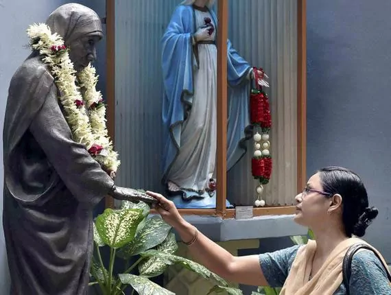 devotee before a statue of Mother Teresa